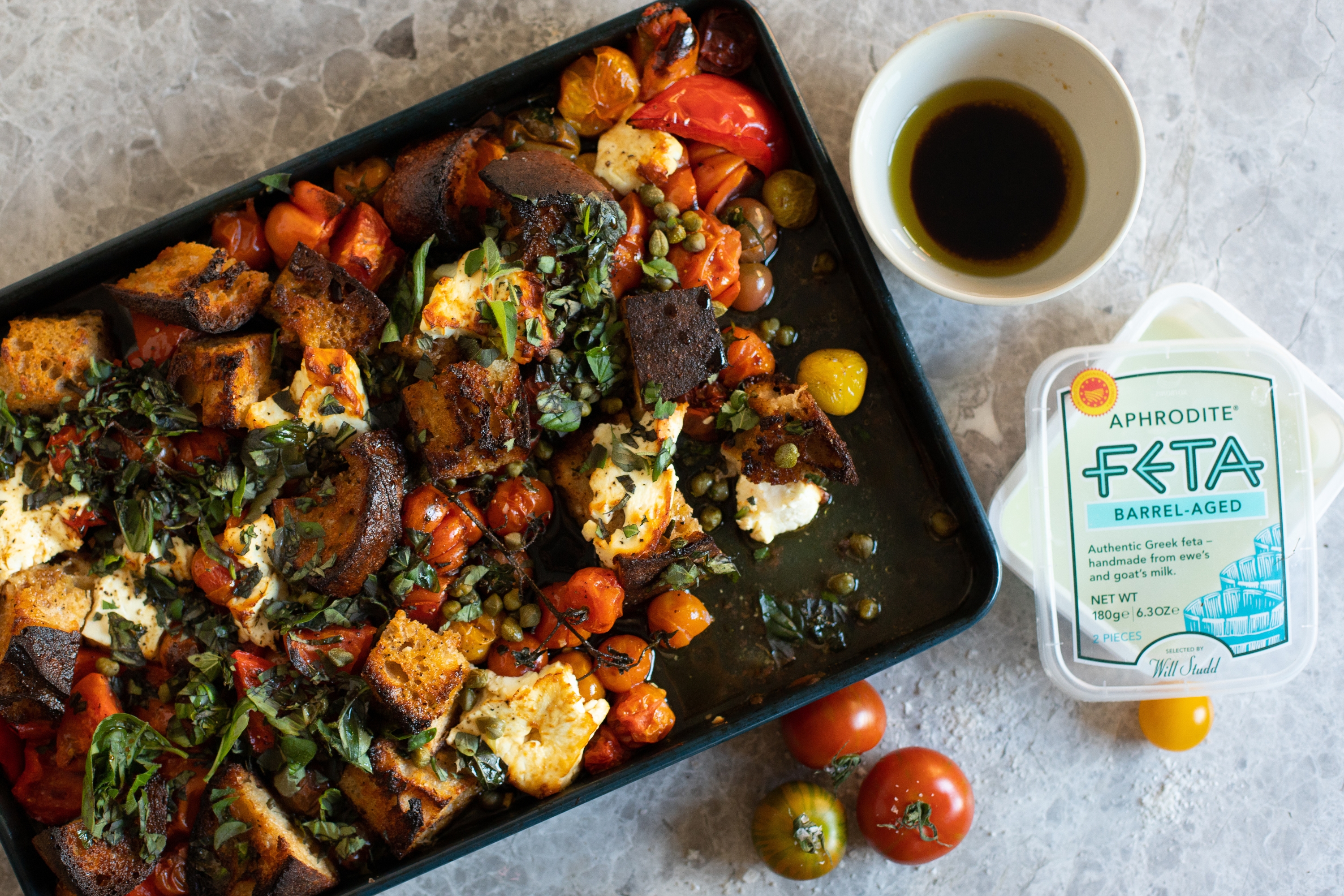 One Tray Feta Bake With Aphrodite Feta On Grey Tile And Feta Packaging